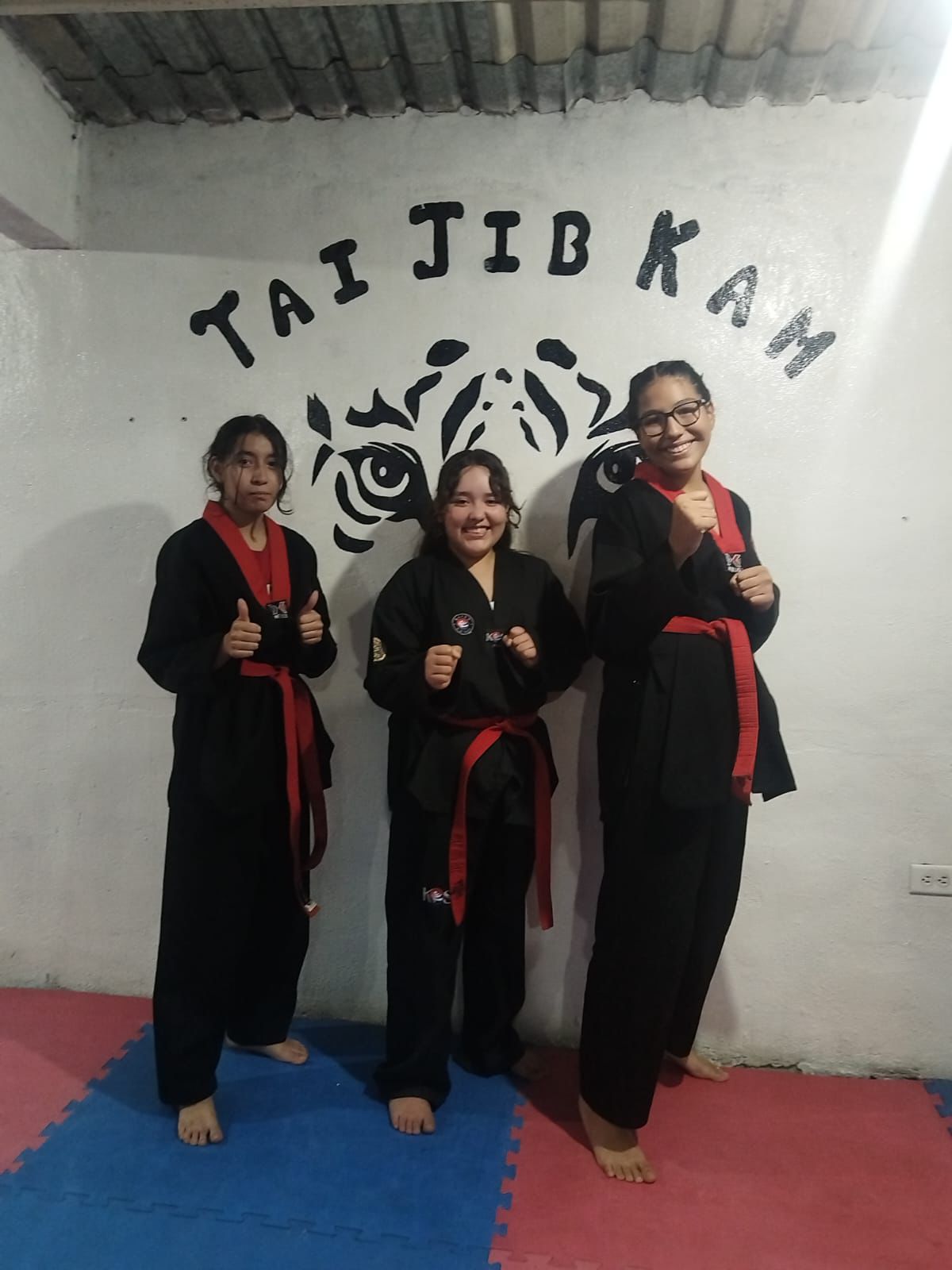 Alumnas cinturón rojo frente al mural del tigre